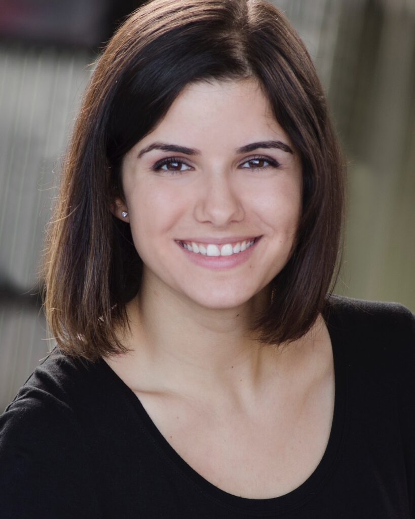A woman with a dark brown hair in a shoulder-length bob haircut in a black dress t-shirt.